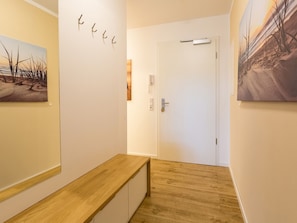 Un couloir avec un banc en bois, une porte et deux tableaux accrochés au mur.