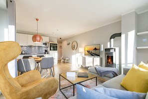 Ein modernes Wohnzimmer mit Sofa, Ohrensessel, Couchtisch und Kamin.