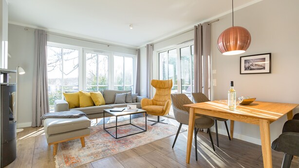 Een moderne woonkamer met een bank, fauteuils, een salontafel en een eettafel.