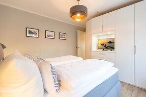 Ein Schlafzimmer mit zwei Betten, einem Kleiderschrank und einem Spiegel, der den Sonnenuntergang widerspiegelt.