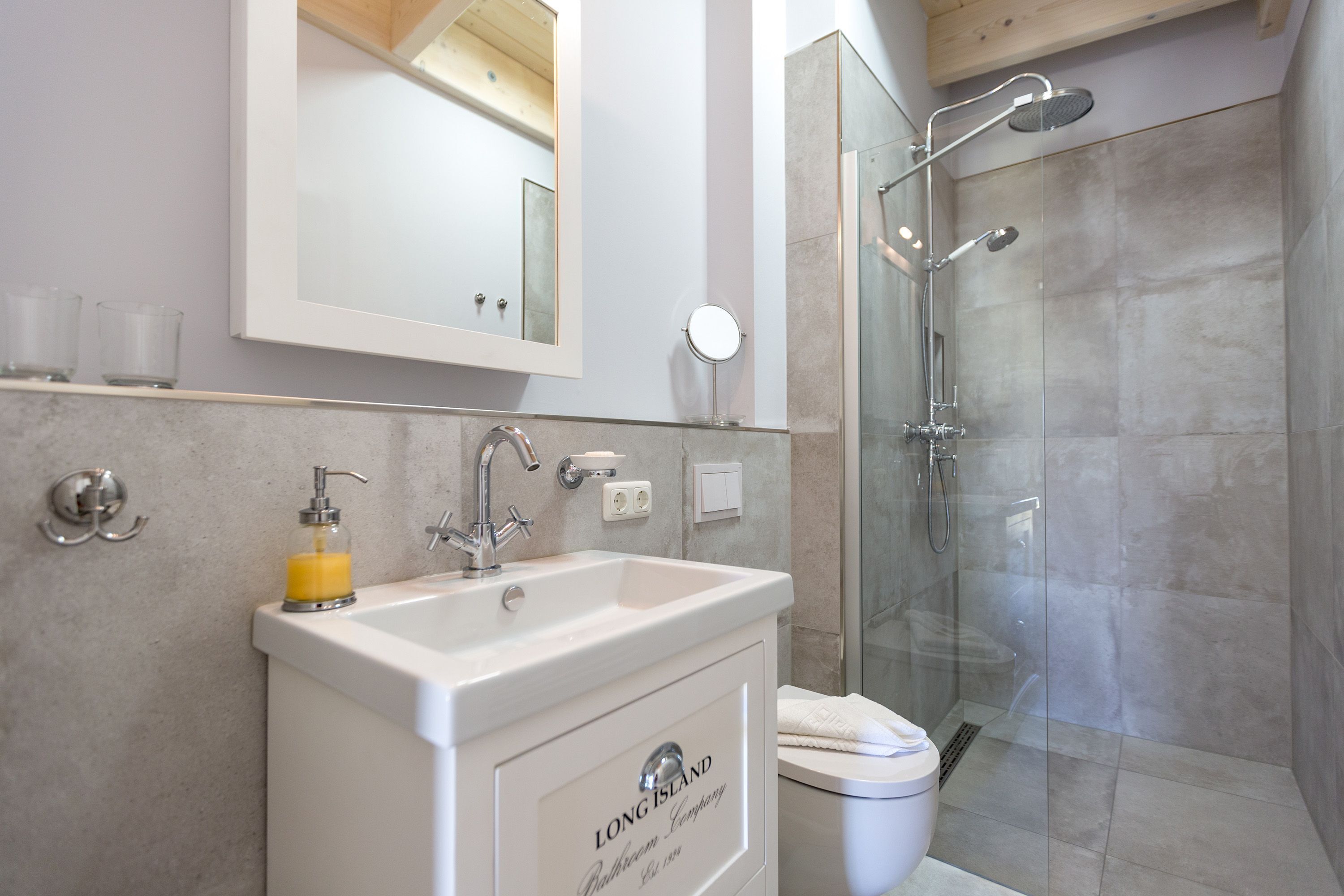 A bathroom with a sink, mirror, and shower.
