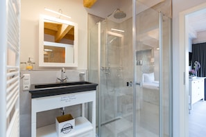 A modern bathroom with a glass-enclosed shower, a white vanity with a black countertop, and a mirror above the sink. - Domicile Düne 8, App. 7 (Heringsdorf)