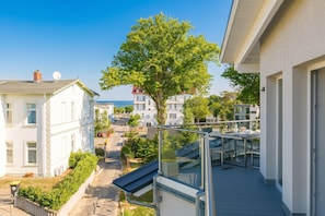 Een woongebouw met balkon, boom en uitzicht op andere gebouwen.