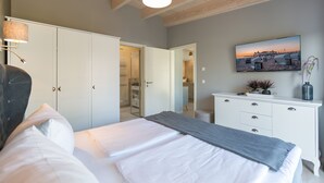 A bedroom with a bed, a dresser, a painting, and a closet. - Domicile Düne 8, App. 7 (Heringsdorf)