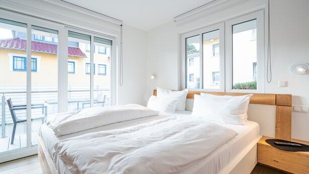 Ein Schlafzimmer mit einem großen Bett, einem hölzernen Kopfteil und einem Nachttisch mit einer Fernbedienung.