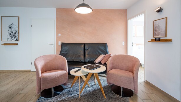 A modern living room with a sofa, two armchairs, a coffee table, and a pendant light. - Domicile Düne 8, App. 3 (Heringsdorf)