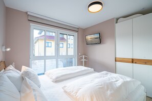 Une chambre à coucher comprenant un lit, une fenêtre, un téléviseur fixé au mur et une armoire.