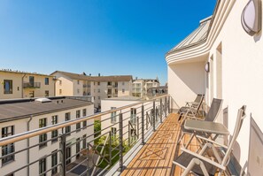 Un balcon donnant sur les bâtiments voisins, avec une balustrade et du mobilier d’extérieur.