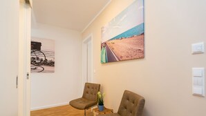 A room with two brown chairs, a small table with a plant, and a painting of a beach scene on the wall. - Quartier am Kurpark, app. 08 (Heringsdorf)