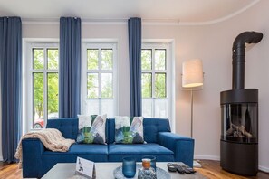 Sala de estar com um sofá azul, uma luminária e uma lareira.