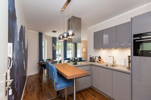 Uma cozinha moderna com armários cinza, uma mesa de jantar de madeira e banquetas azuis.