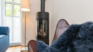 Ein Zimmer mit Kaminofen, einem blauen Sofa und einer Stehlampe.