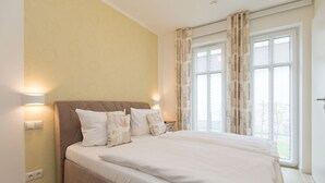 A bedroom with a large bed, two bedside lamps, and a window with curtains. - Quartier am Kurpark, app. 02 (Heringsdorf)