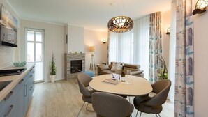A modern dining area with a round table, chairs, a chandelier, a fireplace, and a sofa. - Quartier am Kurpark, app. 02 (Heringsdorf)