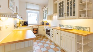 Una cocina con armarios blancos, encimera de madera y suelo de baldosas.