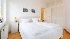 Un dormitorio con cama, lámparas de noche, un radiador y un armario.