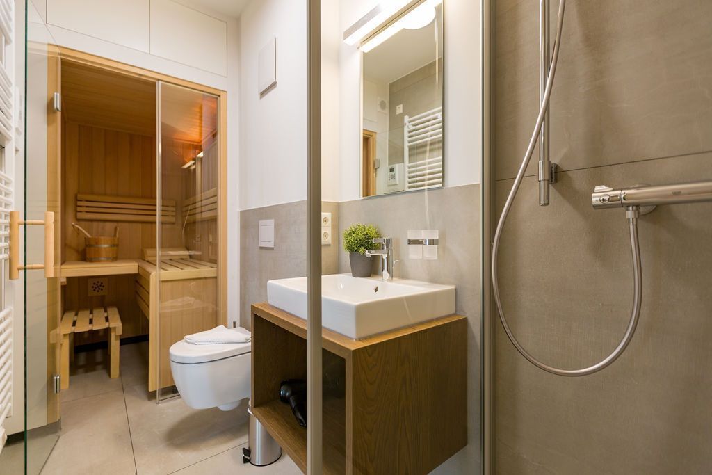 Une salle de bain moderne avec une douche à parois de verre, un meuble-lavabo en bois et des toilettes.