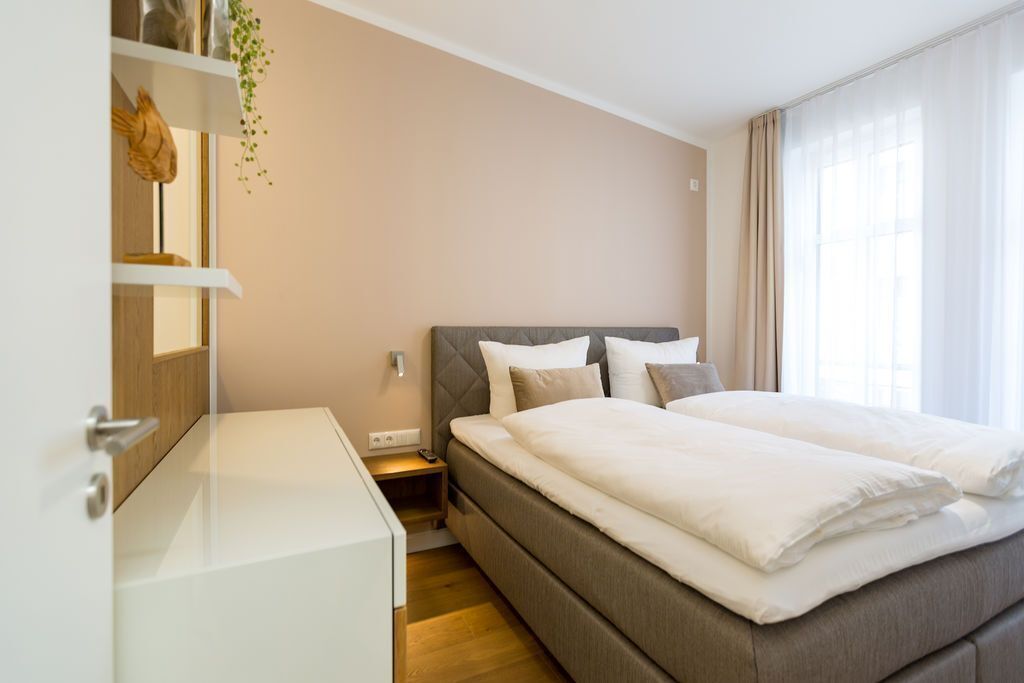 Una camera da letto moderna con un letto grande, un comodino, una mensola con oggetti decorativi.