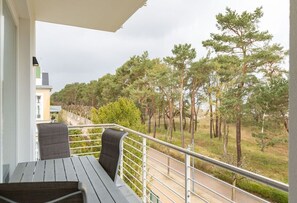 Un balcon donnant sur une zone boisée et une route.