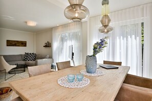 A dining area with a wooden table, two chairs, a vase with flowers, and a laptop on the table. - Vacation cottage Hygge Hus (Sellin/Usedom)
