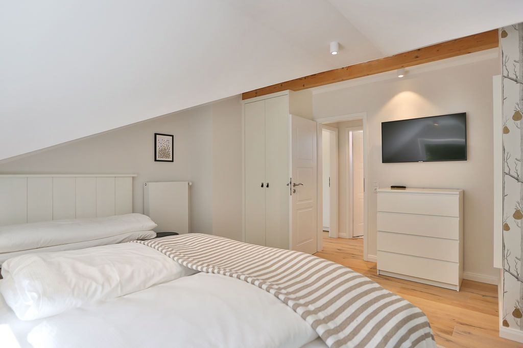Une chambre à coucher comprenant un lit, une télévision, une commode et une armoire.
