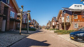 Una strada residenziale con case moderne, una strada asfaltata e auto parcheggiate.