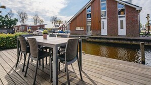 Un edificio moderno con ampie finestre e facciata in legno, vicino a una superficie d'acqua tranquilla.