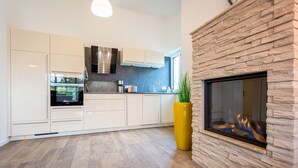 Een moderne keuken met witte kasten, een ingebouwde oven en een stenen haard.