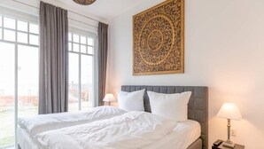 Une chambre d’hôtel avec un grand lit, deux lampes de chevet, une fenêtre avec des rideaux et un élément décoratif mural.