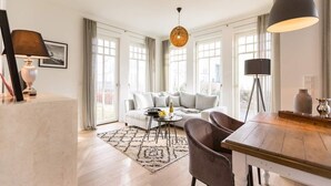 Un salon moderne comprenant un canapé, une table basse, une table à manger et un luminaire suspendu.