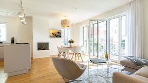 A modern living room with a sofa, a dining table with chairs, and a kitchen area. - Quartier Eichenweg, app. 3 (Heringsdorf)