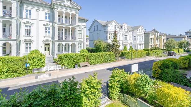 A row of stately, white, multi-story buildings with classic architecture, a well-maintained sidewalk, and lush greenery. - Quartier Eichenweg, app. 3 (Heringsdorf)