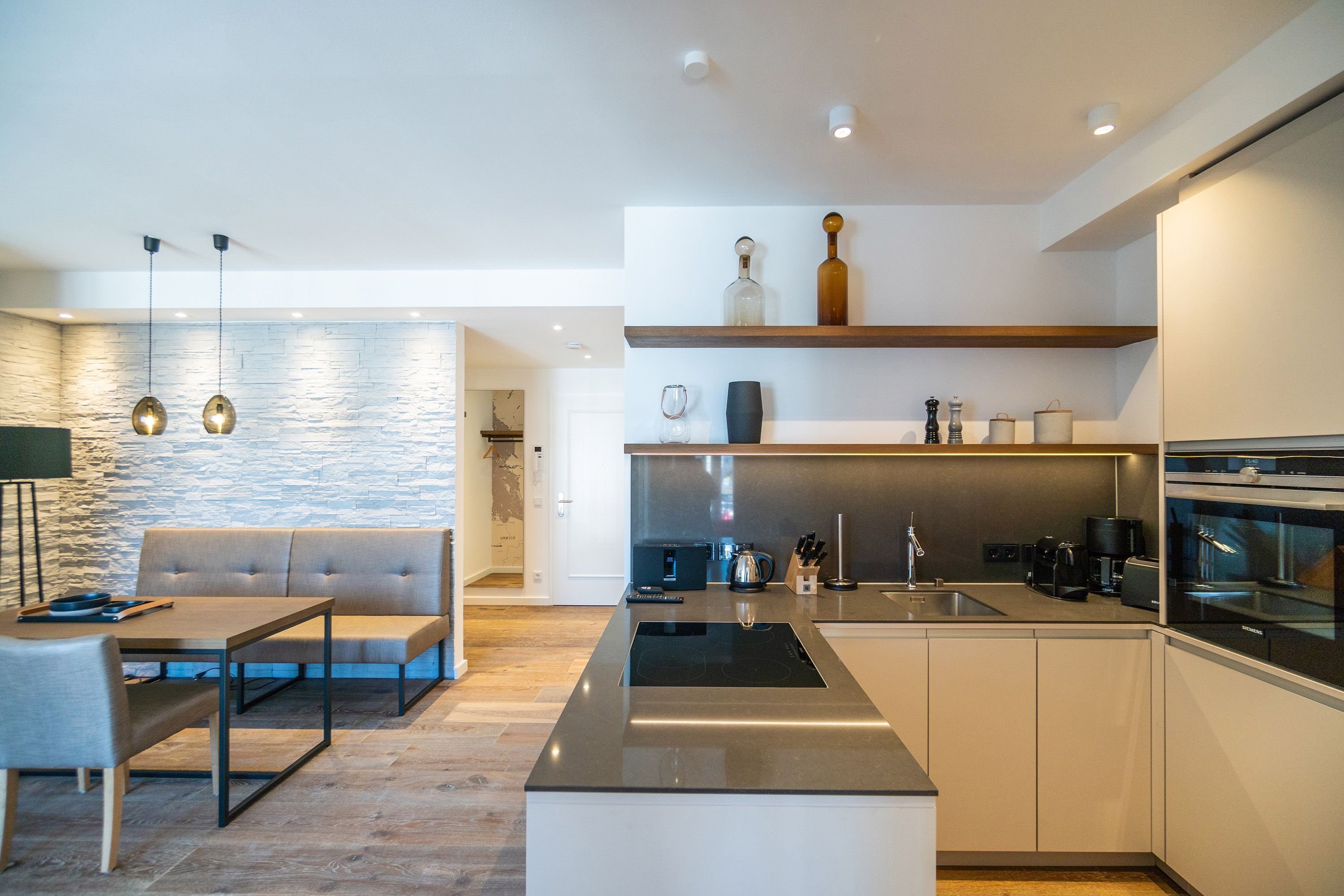 Una cocina moderna con una isla central, electrodomésticos integrados y un comedor con sofá y mesa.