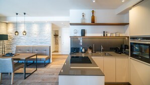 Una cocina moderna con una isla central, electrodomésticos integrados y un comedor con sofá y mesa.