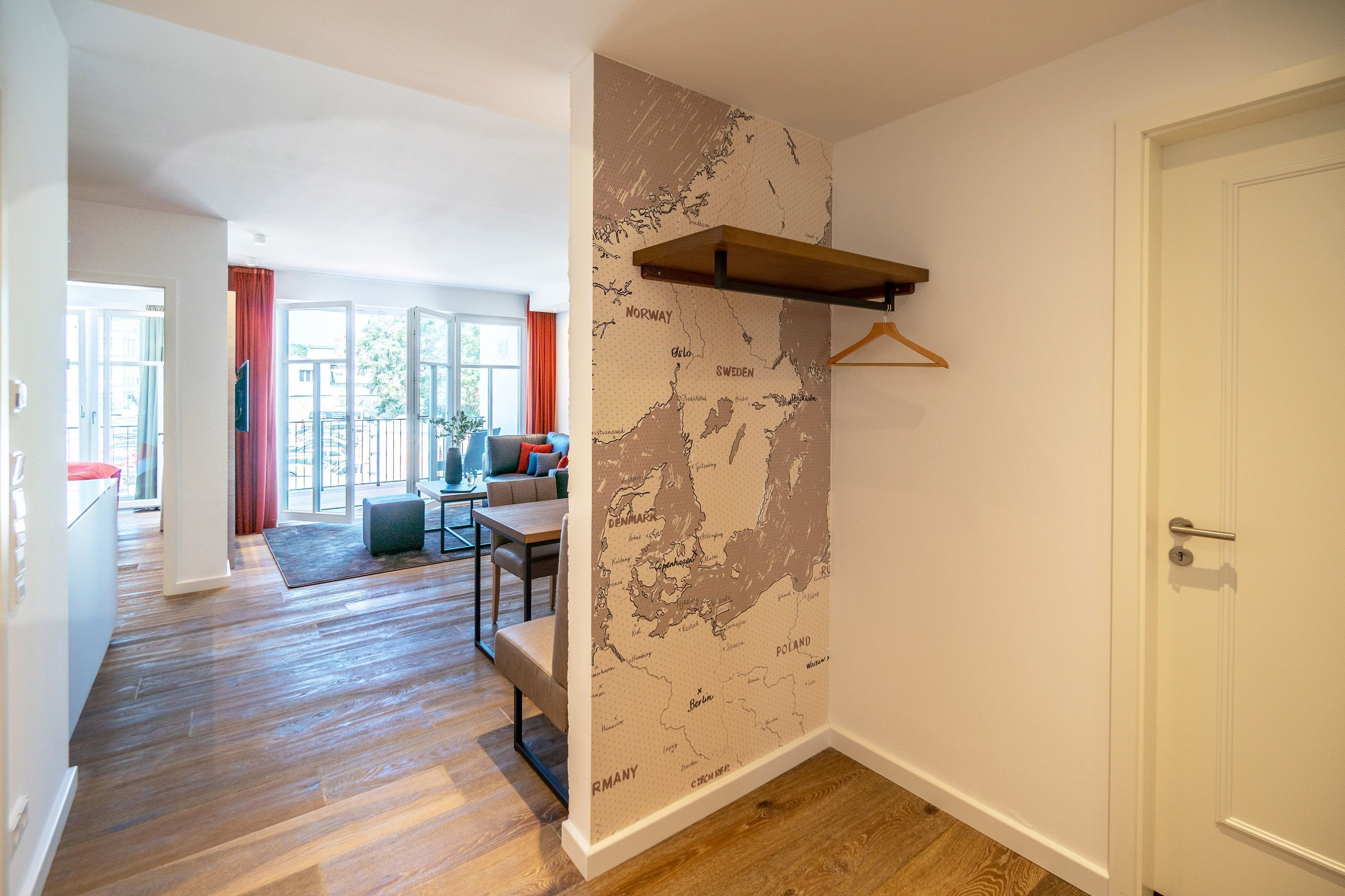 A modern interior with a wooden floor, a map wall, a dining area, and a door.