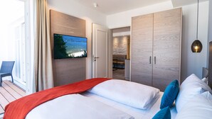 Una habitación de hotel moderna con una cama grande, un televisor montado en la pared y un armario de madera.