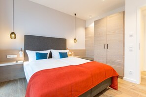 Quarto moderno com uma cama grande, duas mesas de cabeceira e um guarda-roupa.