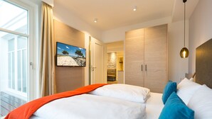 A modern hotel room with a large bed, a television, and a view of the outdoors.
