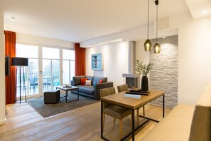 Un salon moderne avec un canapé, une table basse et une table à manger. On y trouve une cheminée et un mur décoratif en pierre.