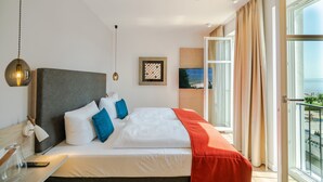 A modern hotel room with a large bed, a desk with a lamp, a framed artwork on the wall, and a balcony with a view. - Beachhouse Bansin, app. 22 (Heringsdorf)