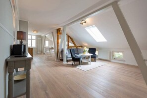 Apartamento amplo estilo loft, com pé direito alto, vigas de madeira aparentes e claraboias.