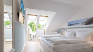 Un dormitorio con una cama grande, un tragaluz y un cuadro de una playa.