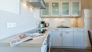A modern kitchen with white cabinets, a built-in oven, and a coffee maker. - Quartier am Fischerstrand, App. 3 (Heringsdorf)