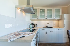 A modern kitchen with white cabinets, a built-in oven, and a coffee maker. - Quartier am Fischerstrand, App. 3 (Heringsdorf)