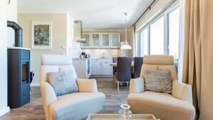 A modern living room with two sofas, a coffee table, a fireplace, and a kitchen in the background. - Quartier am Fischerstrand, App. 3 (Heringsdorf)