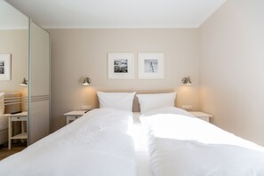 Ett hotellrum med en stor säng, sängbord, en spegel och två inramade tavlor på väggen.