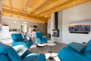 Una sala moderna con sofás azules, una chimenea y una cocina al fondo.