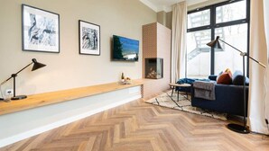 A modern living room with a wooden herringbone floor, a fireplace, a sofa, a coffee table, and framed artwork on the walls. - Villa Bellevue, App. 03 (Heringsdorf)