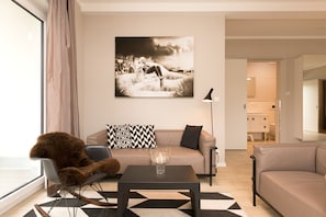 Uma sala de estar moderna com um sofá, uma poltrona, uma mesa de centro e um quadro grande fixado na parede.