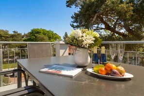Une table avec un livre, un vase de fleurs, une assiette de fruits et deux bouteilles.